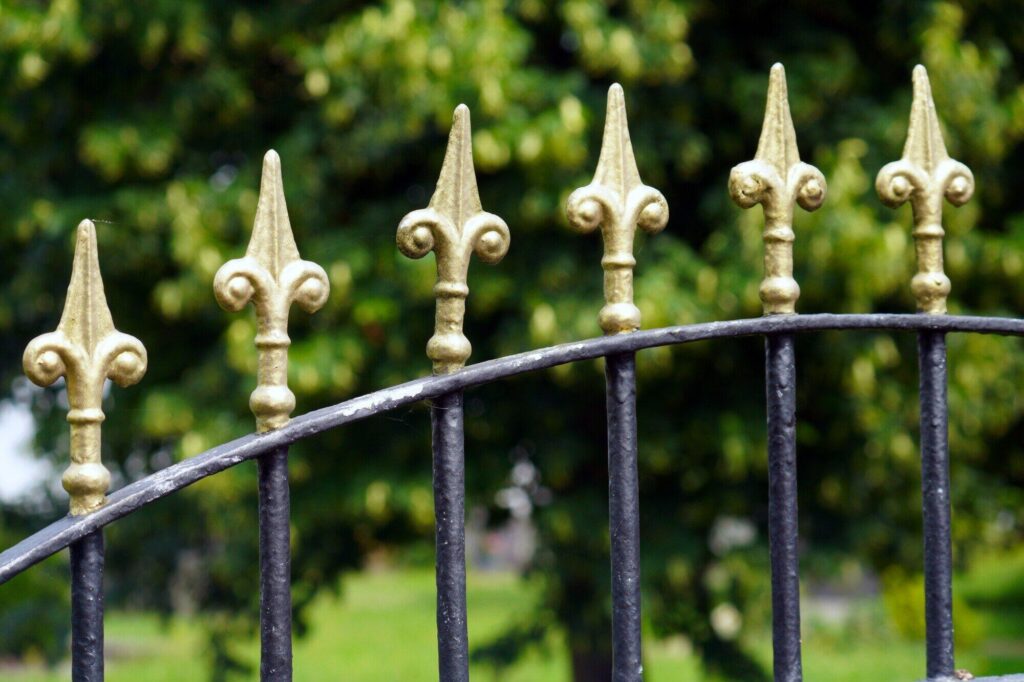 black wrought iron fence with gold fleur de lis at the top